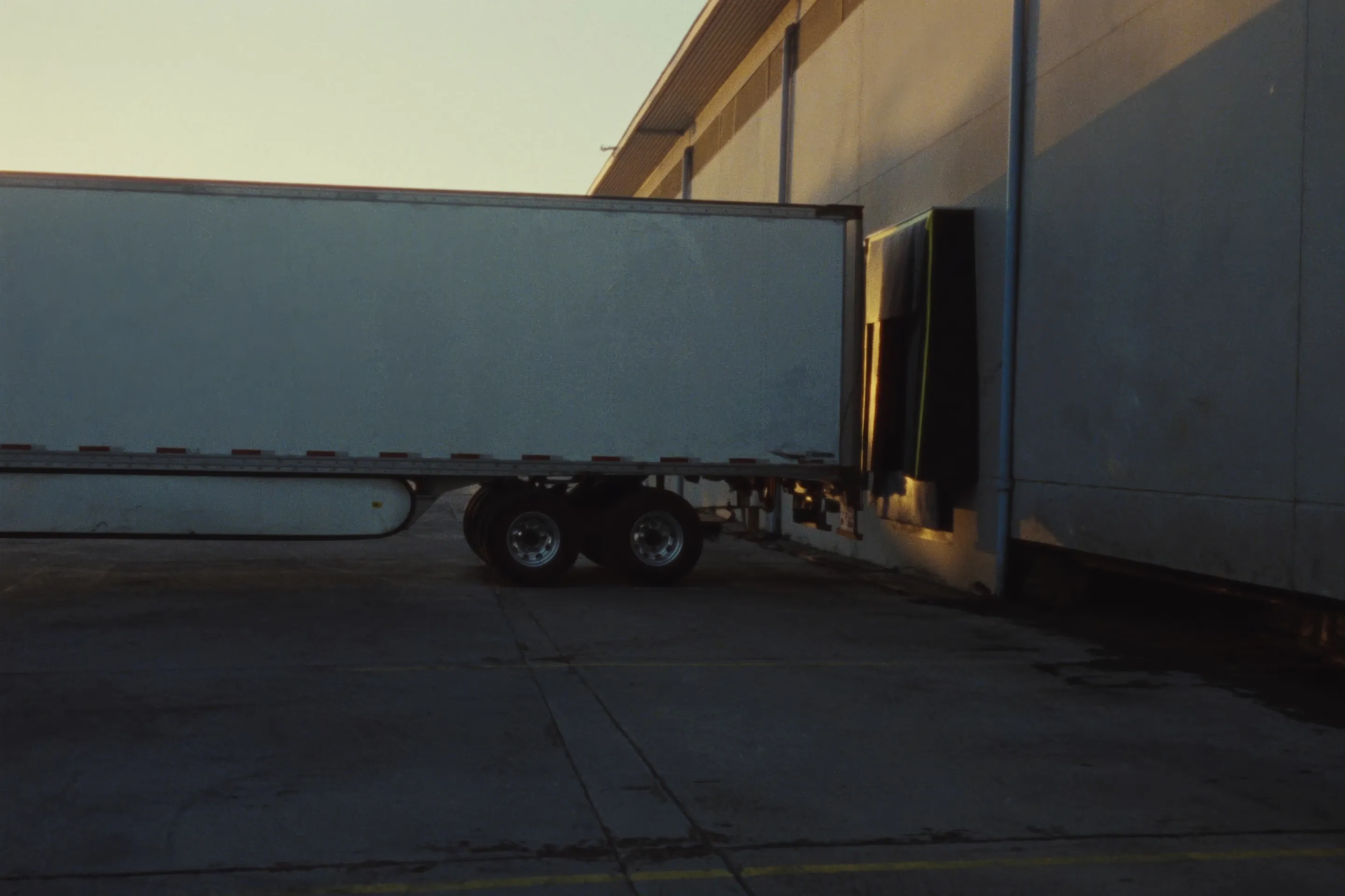 A trailer backed into a loading dock at sunrise