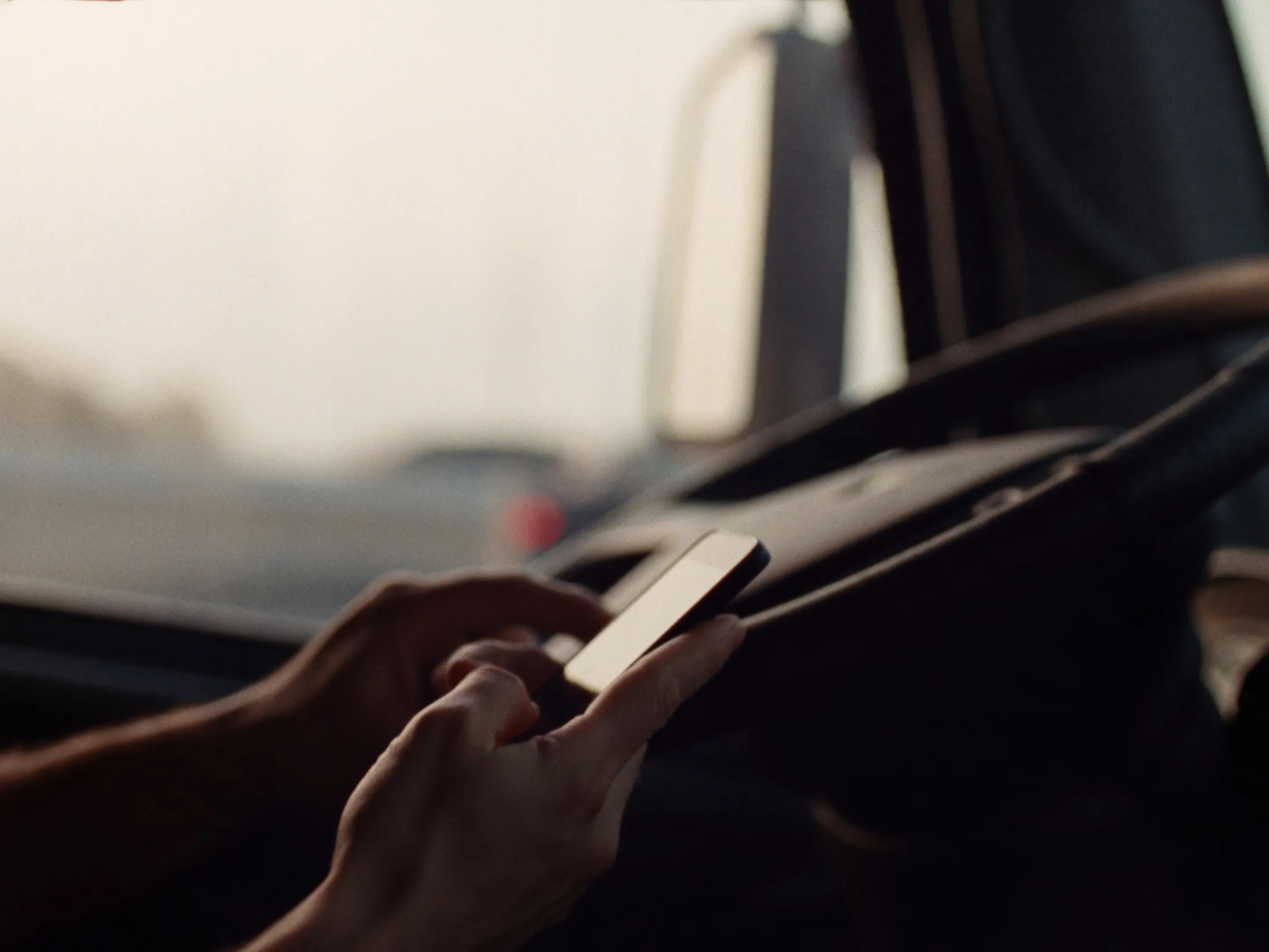 A driver holding a phone in the cab of a truck